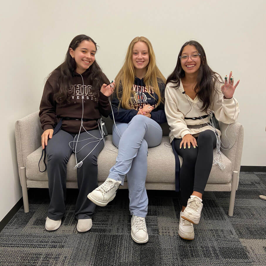 Peer relations lab researchers sitting on a gray couch smiling