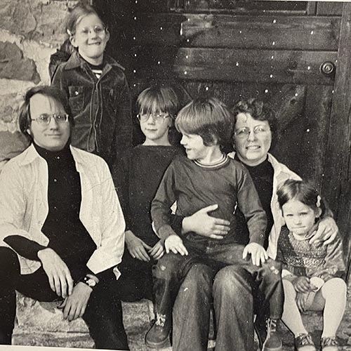 Peter and Anne Beidler sit on the doorstep of the mill with their young family.