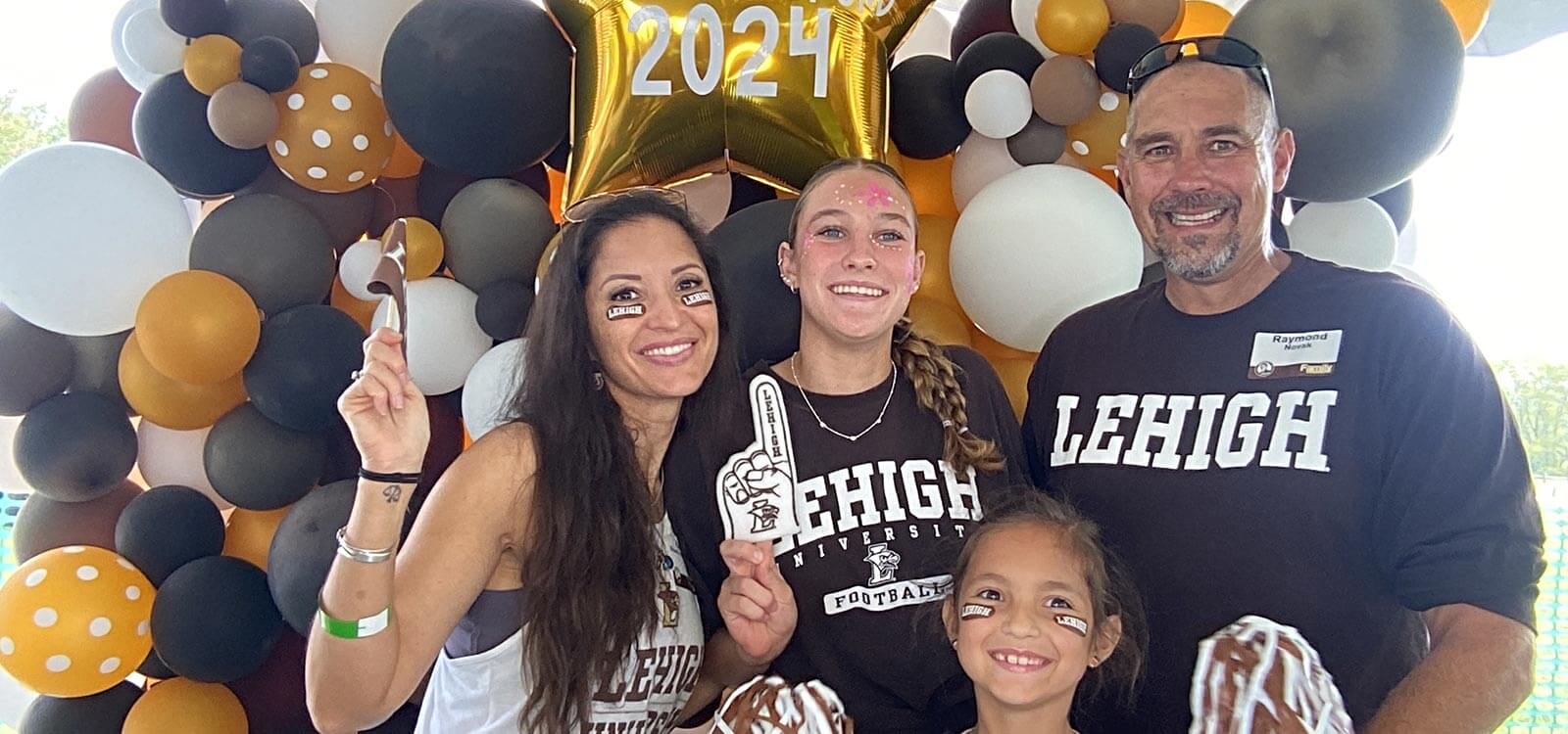 Novak and her family stand in front of a balloon arch that reads ‘Lehigh Family Weekend 2024’ while wearing Lehigh merch.
