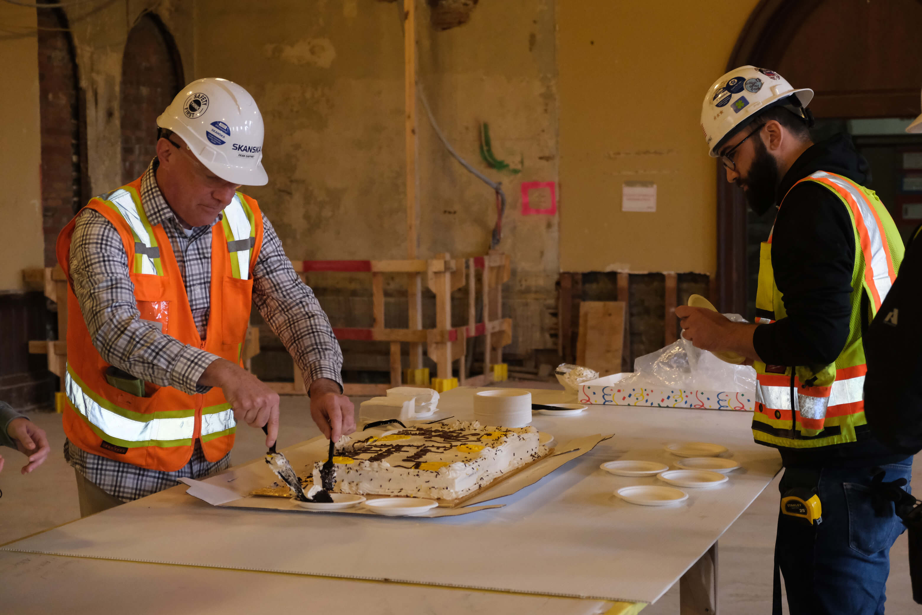 Construction workers cutting a birthday cake