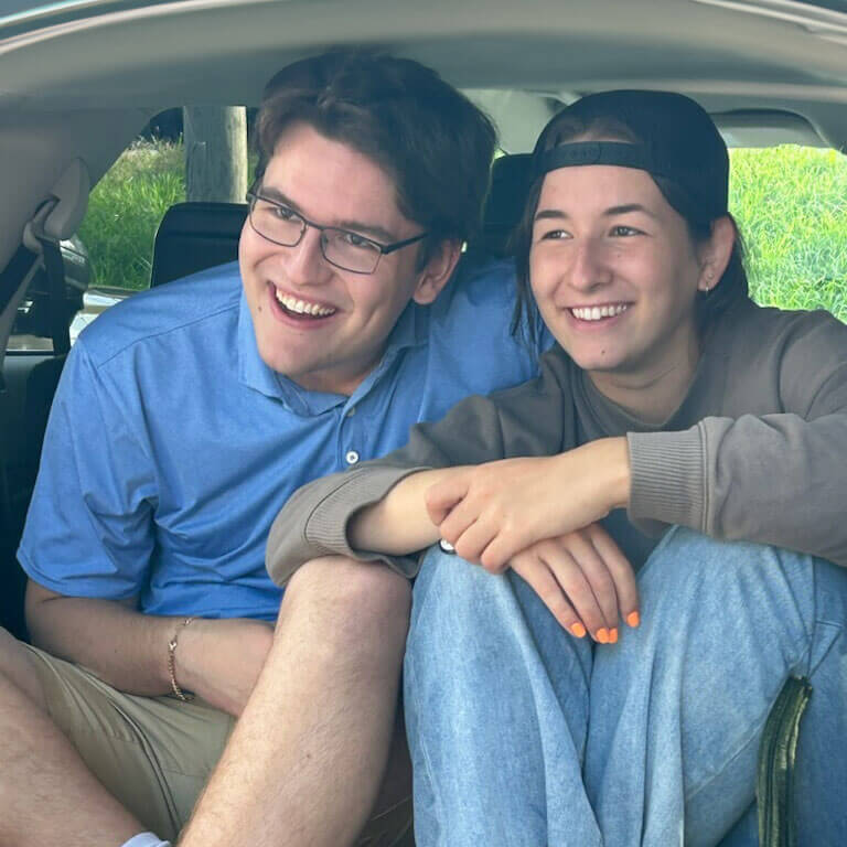 RJ and Cameron sitting in the tailgate of a car