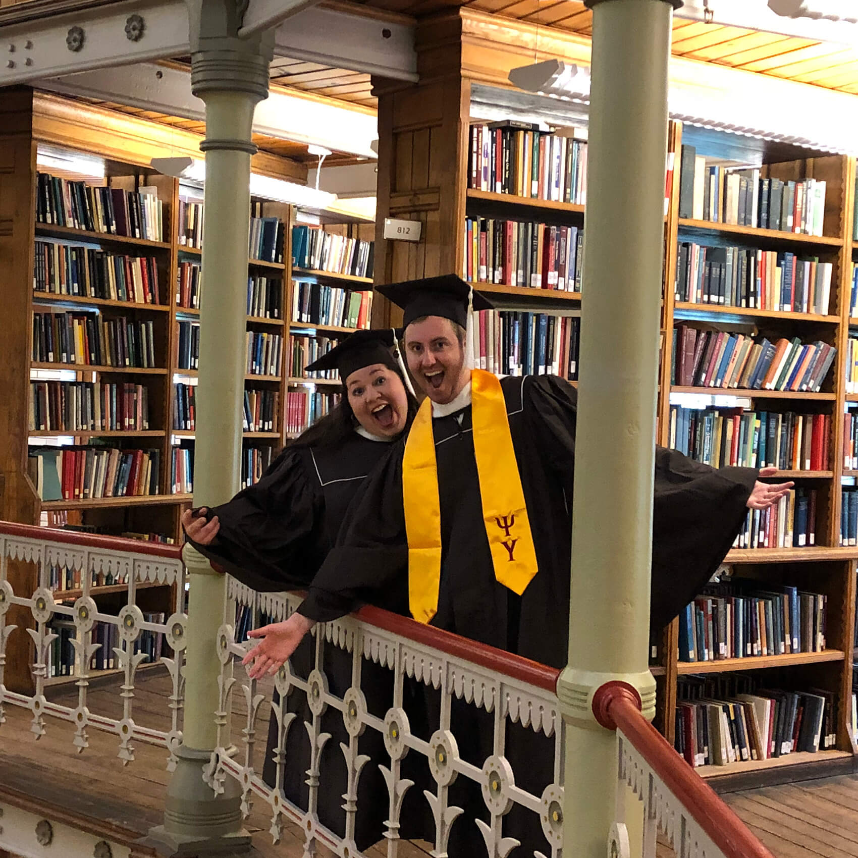 Hanging safely over the railing among the stacks of books at Linderman Library, Christian and Sara pose in their graduation gowns.