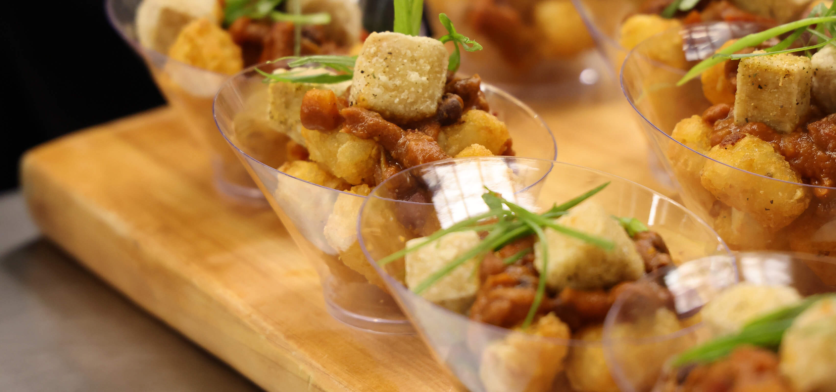 An assortment of small clear bowls filled with chili and green sprigs.