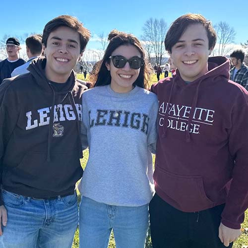 Chris on the left in a Lehigh hoodie. His sister Elizabeth stands in the center in her Lehigh sweatshirt. Michael on the right is in Lafayette gear.