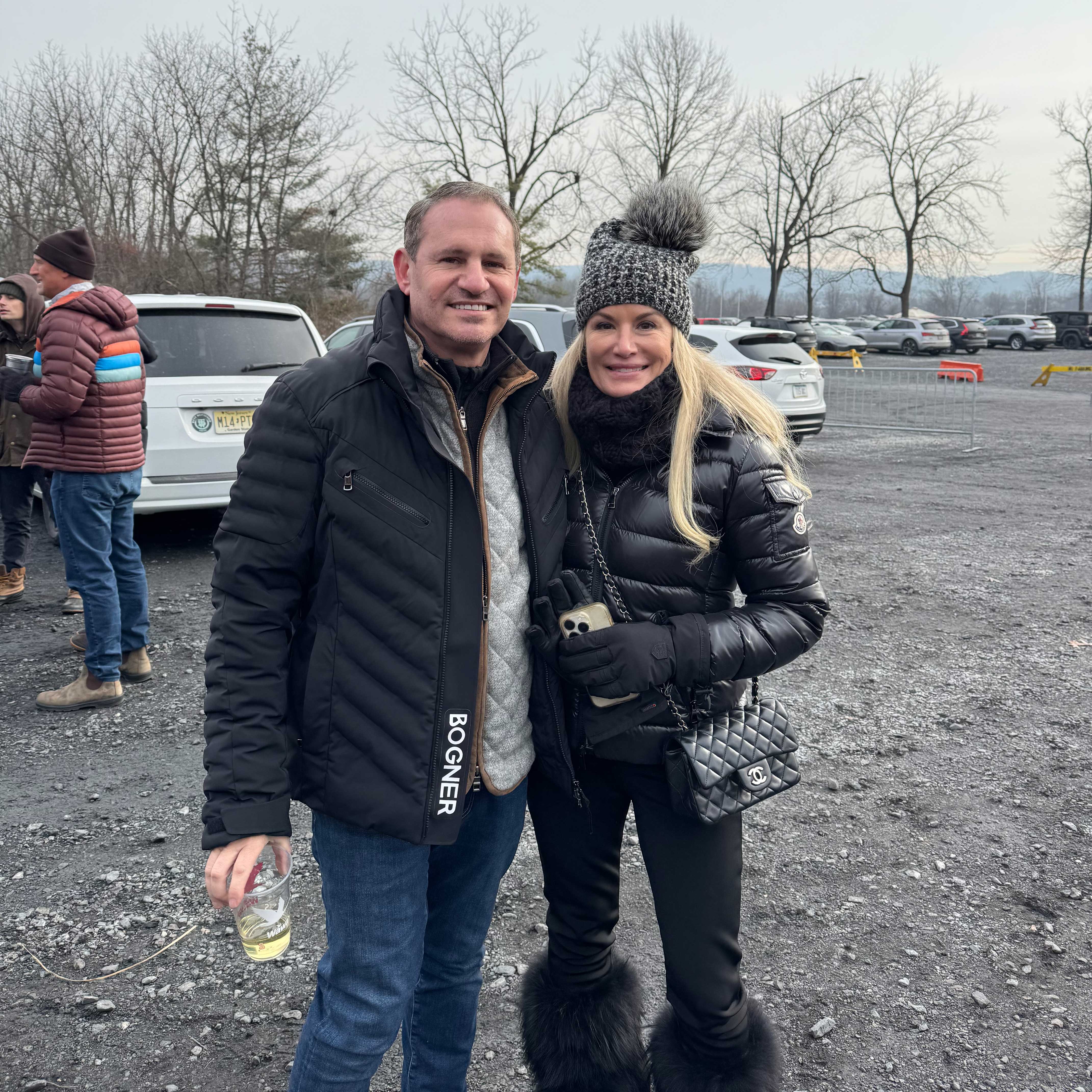 Rob and Candace stand together outside in thick, winter jackets and smile. 