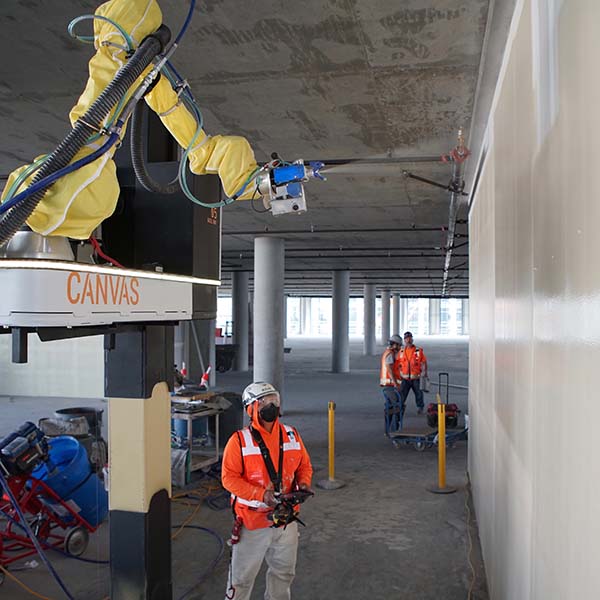 Worker sprays wall with construction robot