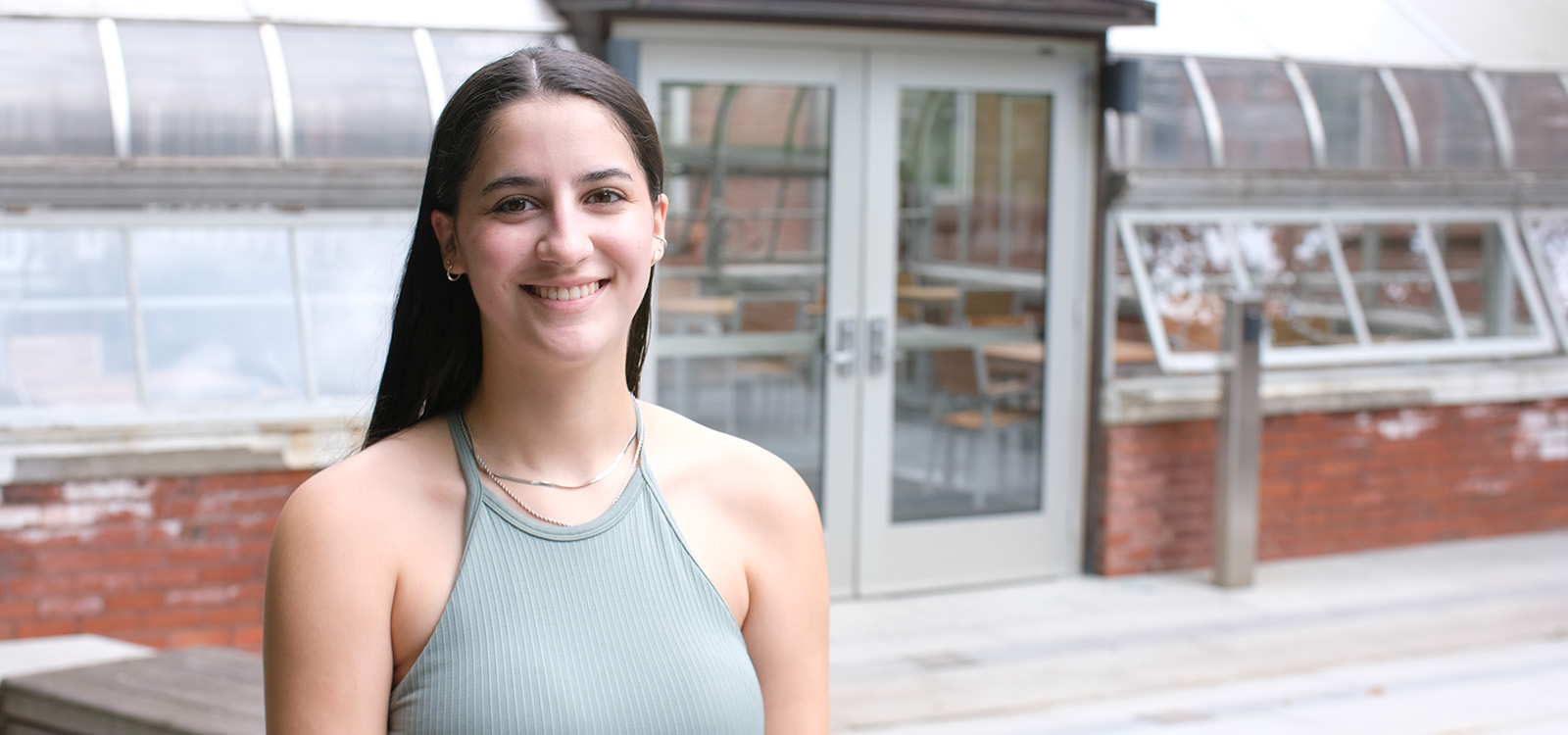 Sofia Schnerr stands outside the greenhouse at Williams Hall