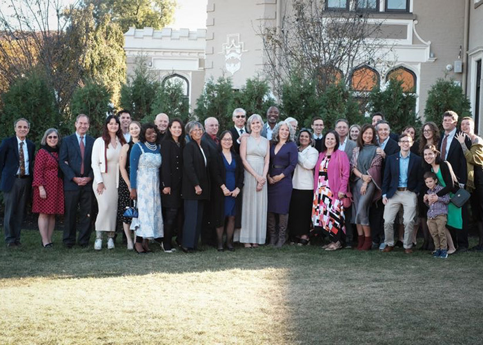 A group of people line up in formal clothes for a wedding photo