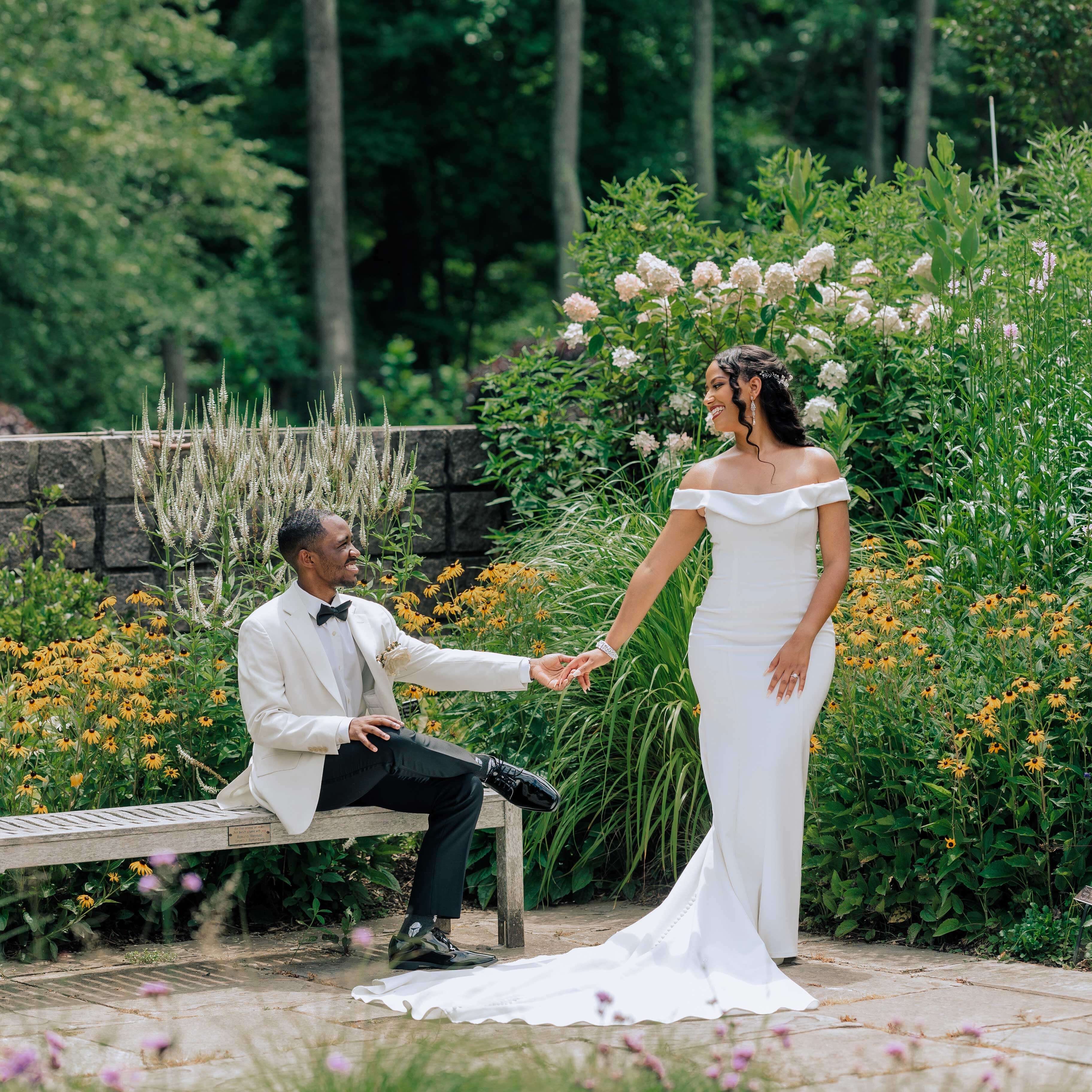 Jones and Taye on their wedding day. Taye wears a long white gown and holds hands with Jones, who wears a white suit jacket.