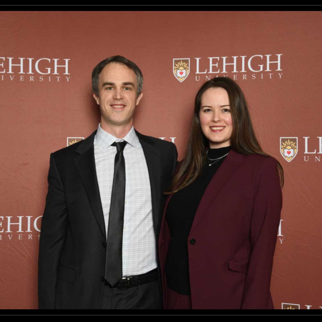 Taylor and Michael stand in front of a Lehigh backdrop. They wear business attire and smile.