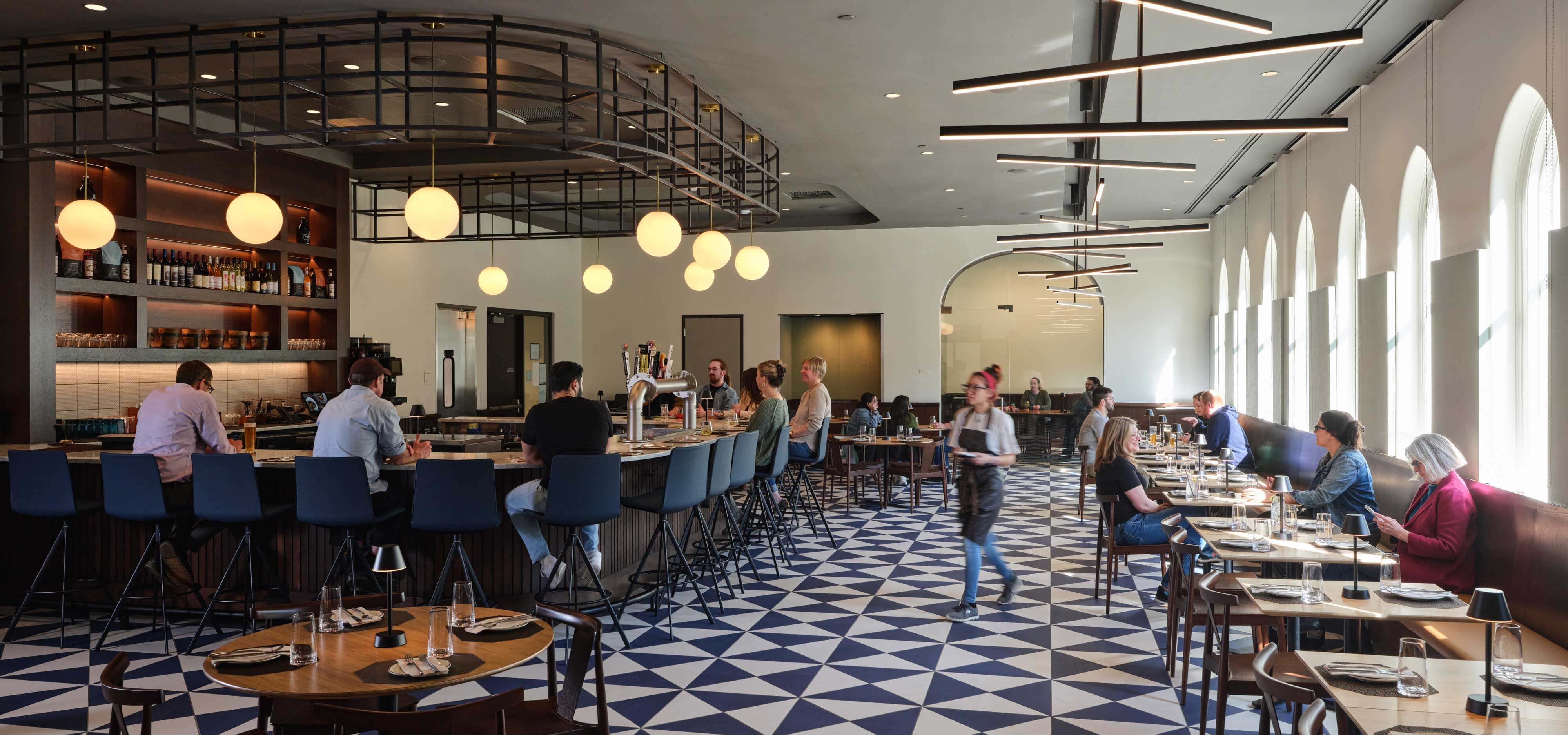 People sit at the bar and at tables for lunch.