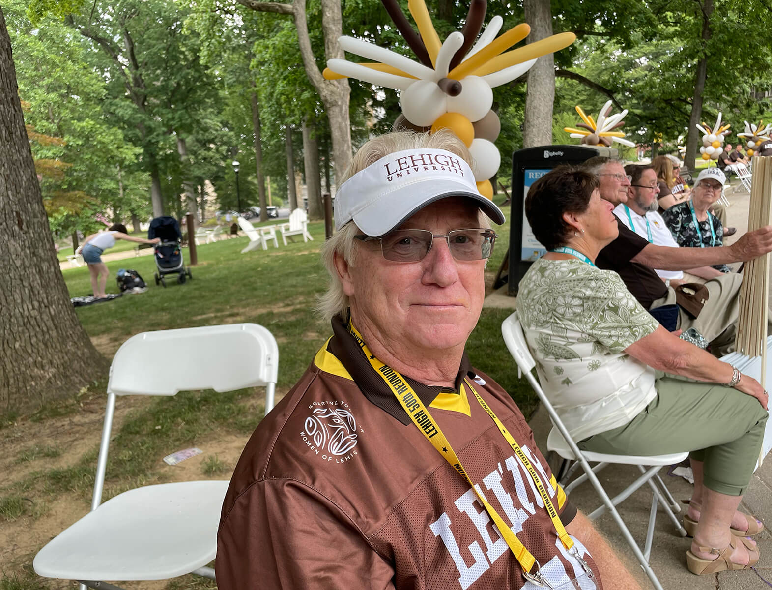 Alumnus sits in a lawn chair at Reunion 2023 wearing a brown Lehigh jersey and lanyard.
