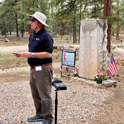 Tom Sulpizio delivers remarks in front of a large gravestone