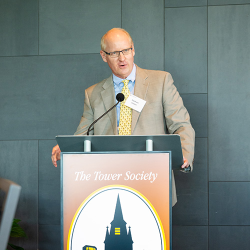 Nathan Urban grips the podium that displays a Tower Society logo