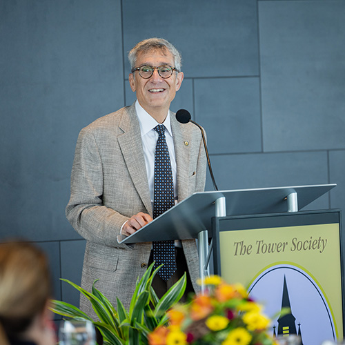Joseph Helble smiles while standing at a podium