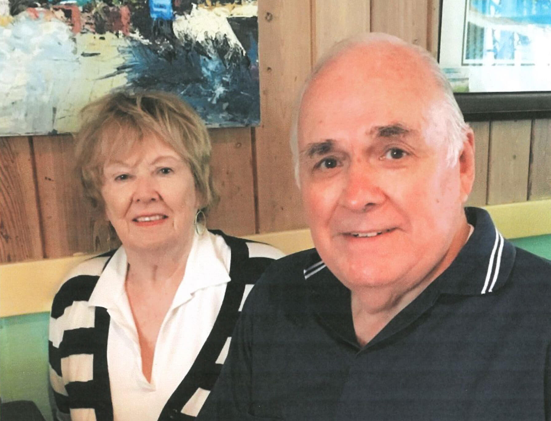 David Van Horn smiles beside his wife Barbara in a green leather booth with wood paneled walls.