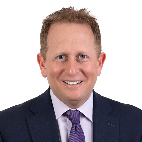 Josh Fiske in a purple shirt and tie and blue blazer