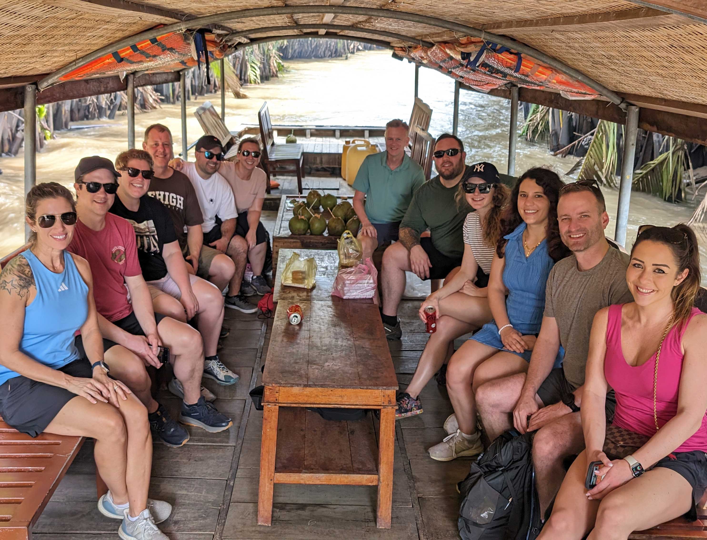 A group of FLEX MBA students sit together on a covered boat on the Mekong Delta river in Vietnam. 