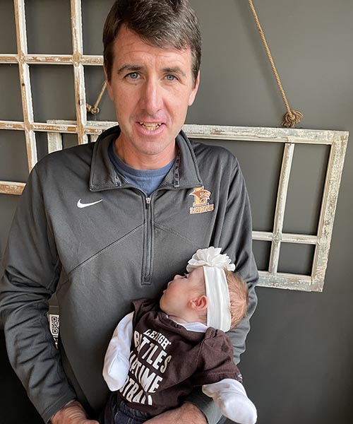 Troy Romanowski ’07 holds his newborn daughter with both in Lehigh gear.