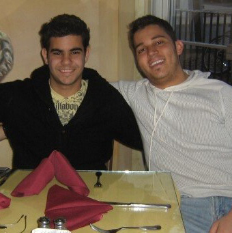 Faris Ghawi and Amer Alnajar sit smiling at a yellow restaurant table with red napkins during their college days.