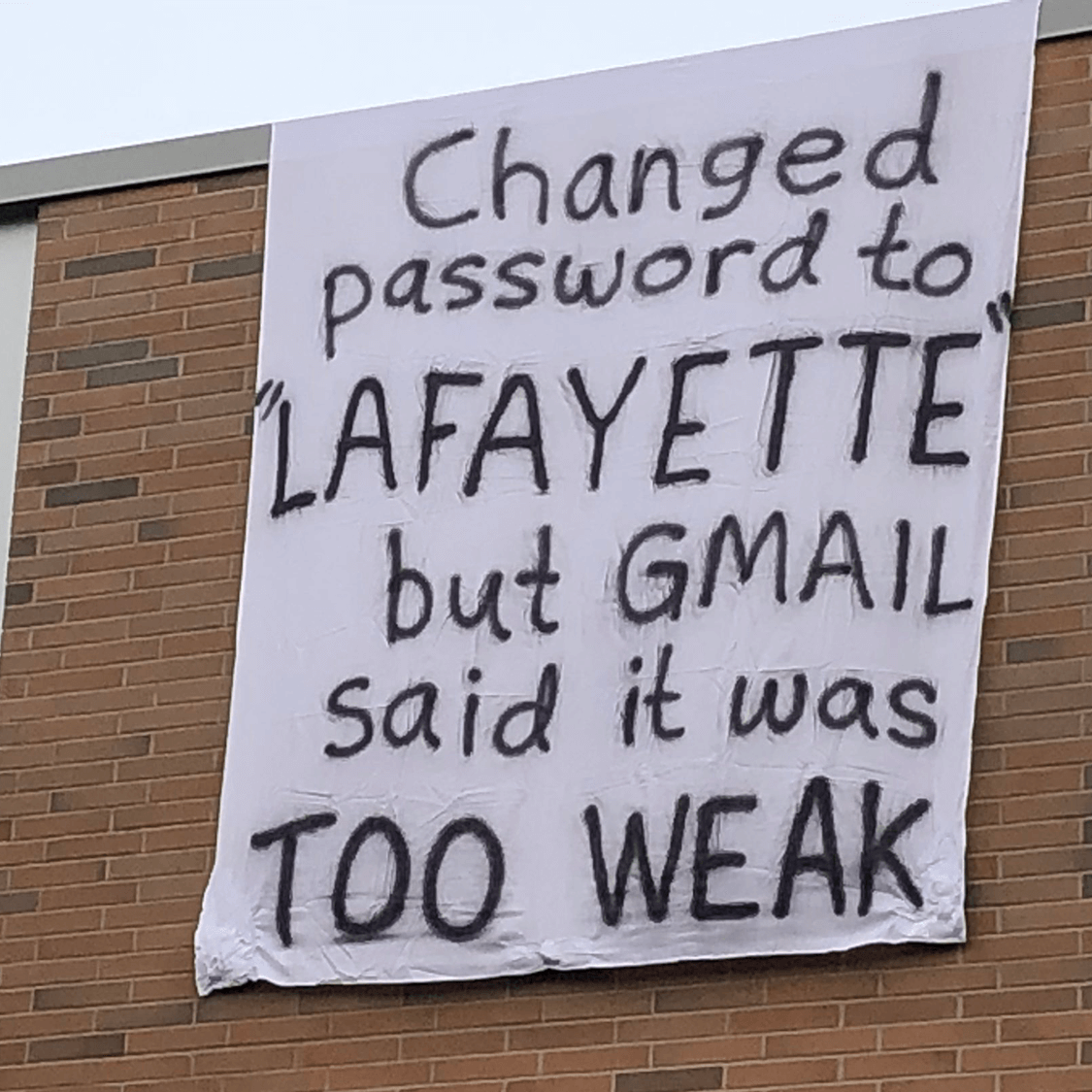 A bedsheet hangs from a building with a taunt, "Changed password to Lafayette but Gmail said it was too weak."