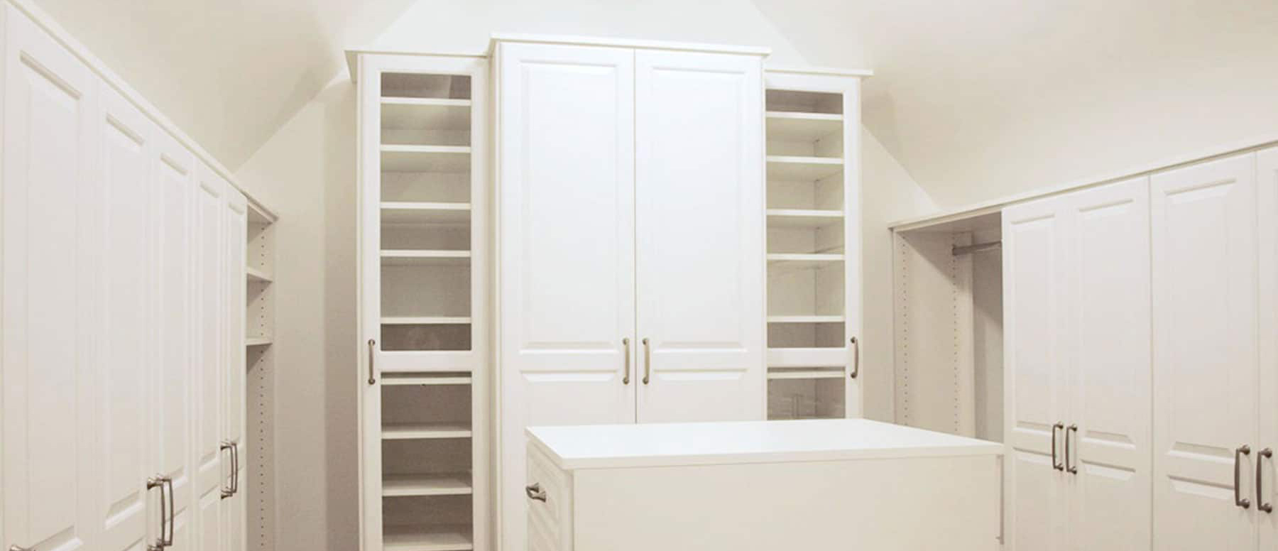 An elaborate white closet with multiple cabinets, drawers, and cubbies.