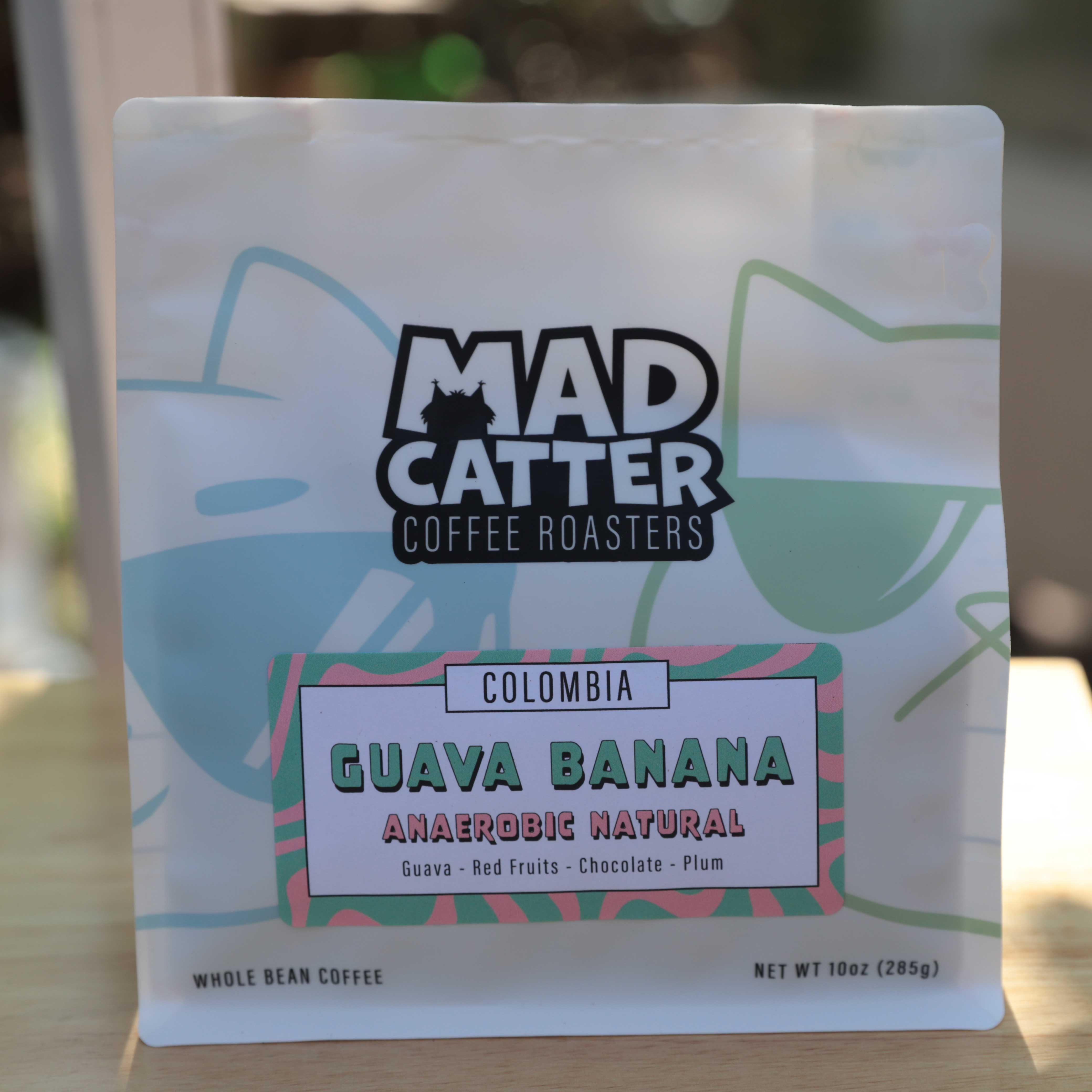 A bag of Mad Catter branded coffee beans in the guava banana flavor. The bag features the outline of cats in sunglasses. 