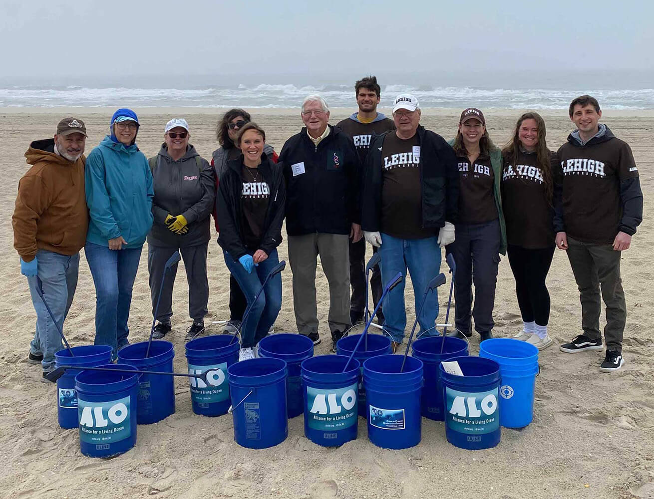 A group of alumni standing together on a sandy beach.