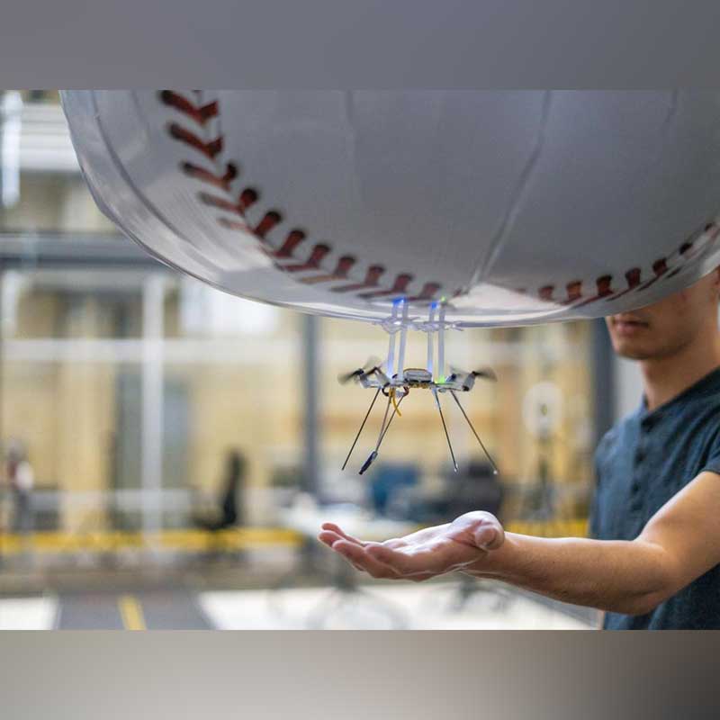 A student puts their hand out to catch a drone in their palm.