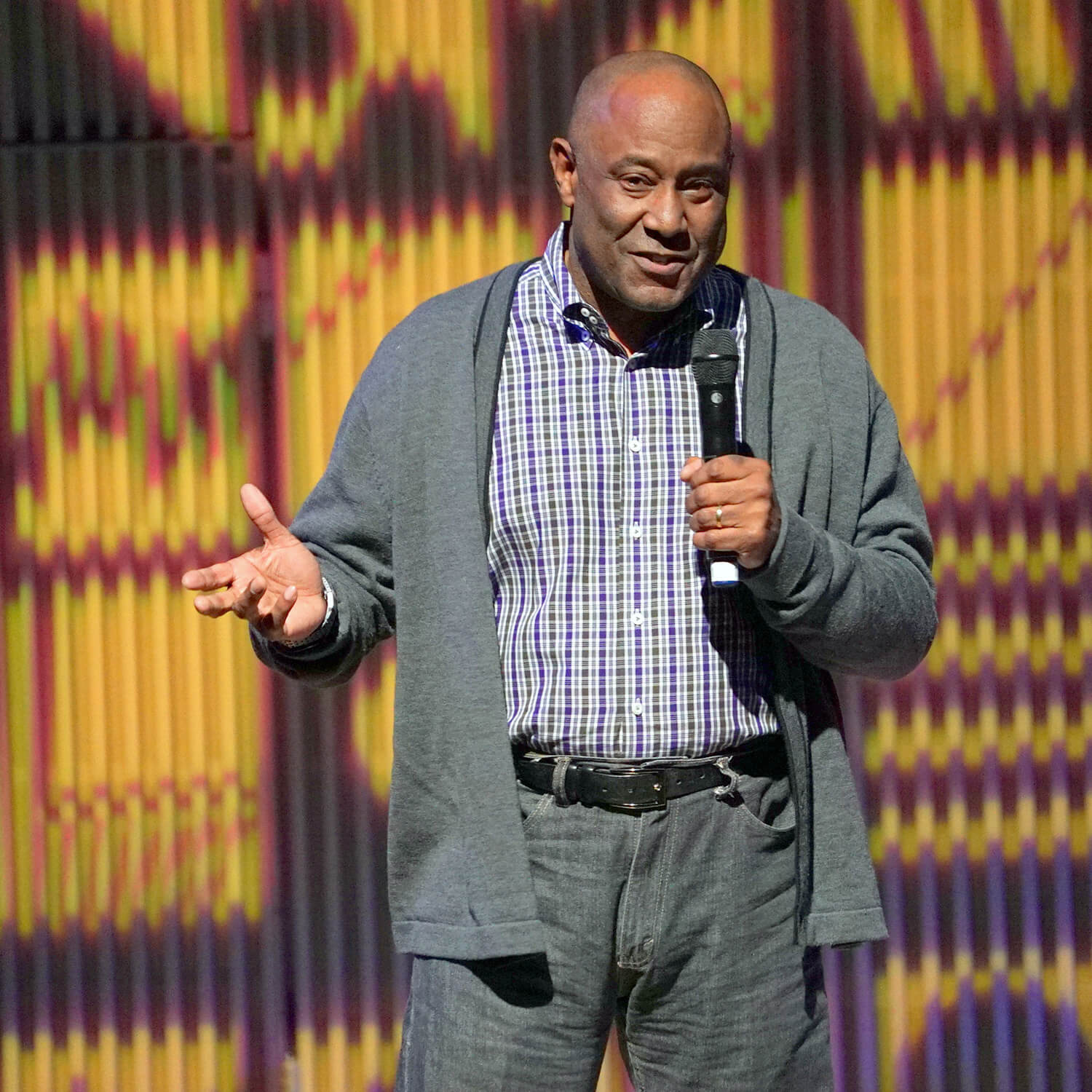 Mount Allen on stage holding a microphone in front of an abstract backdrop