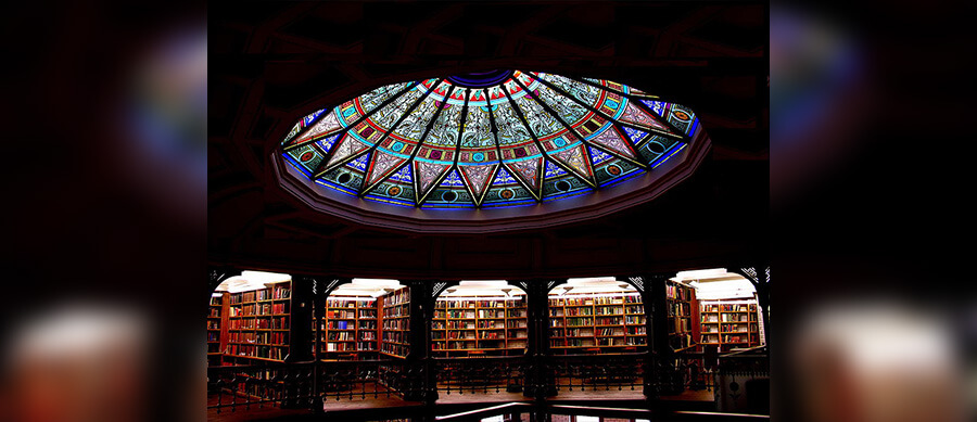 Interior shot of the Linderman Library rotunda, showing the top floor of aisles and the stained glass rotunda glowing above.