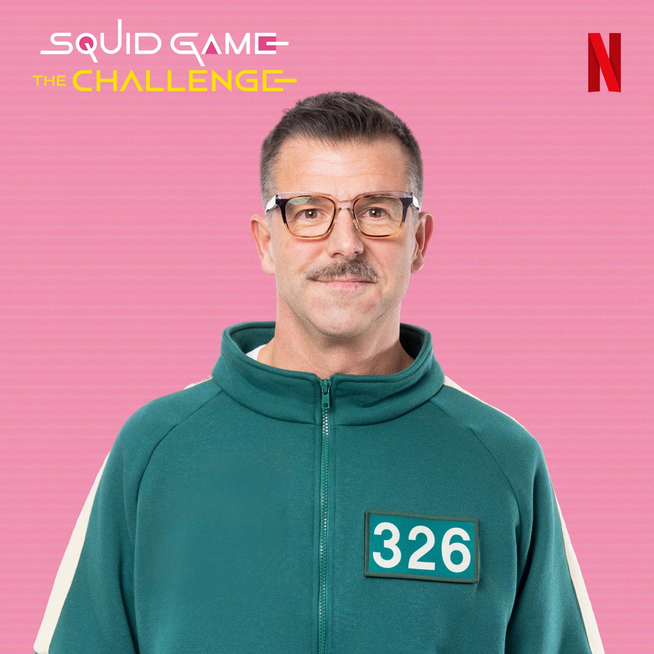 Jason poses for the game show; he wears a zippered green tracksuit with the number 326 on the front of it. 