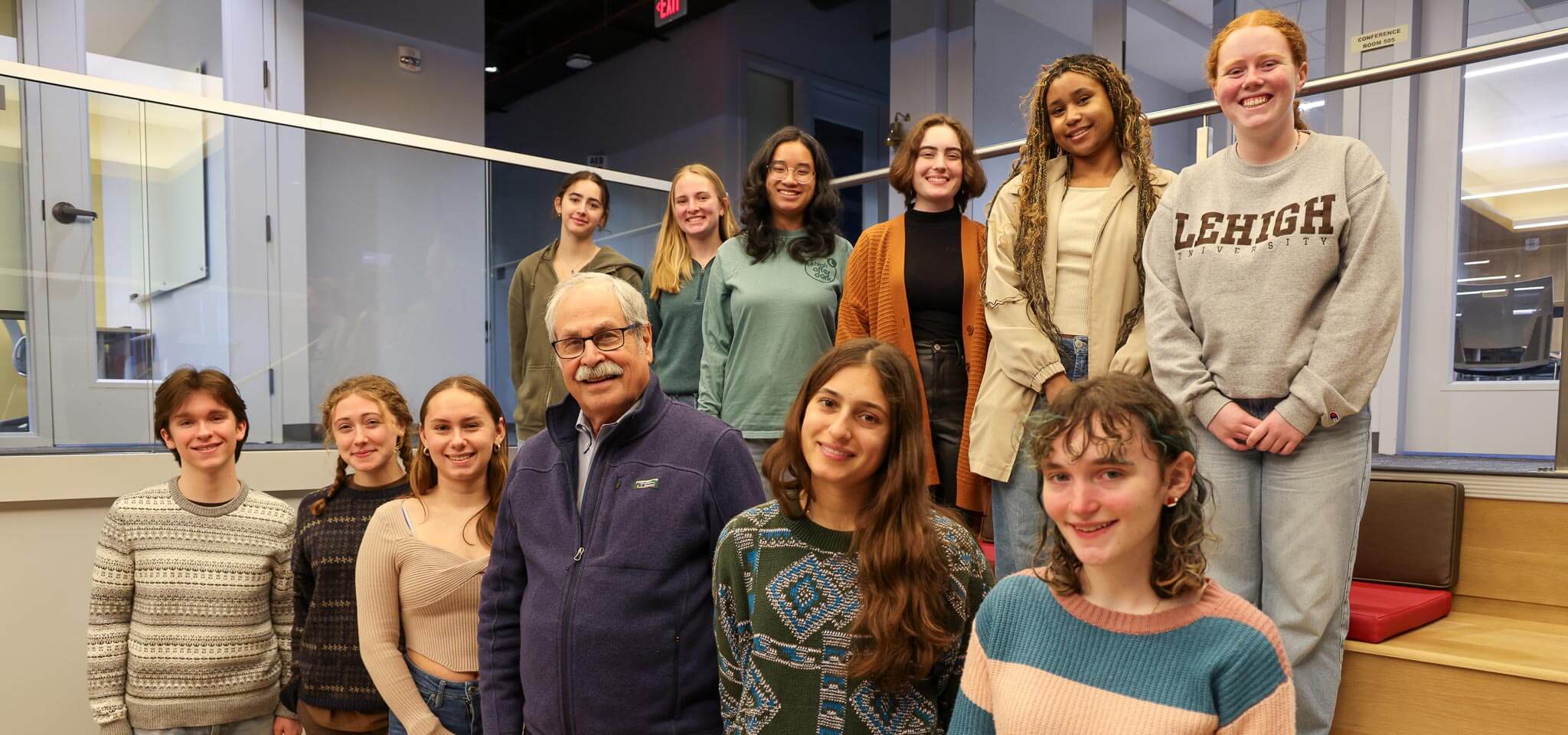 Mark and a group of eleven undergraduate students stand together and smile.