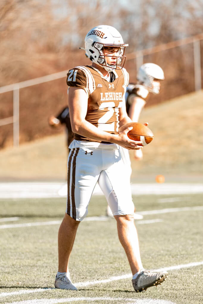 A football player holds a football on the field.