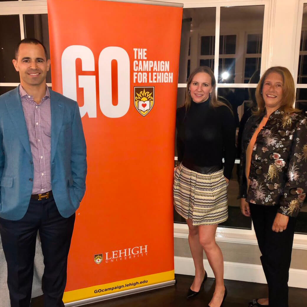 Andrew and Kimberly Handler pose with Dean Dolan next to an orange GO The Campaign For Lehigh banner