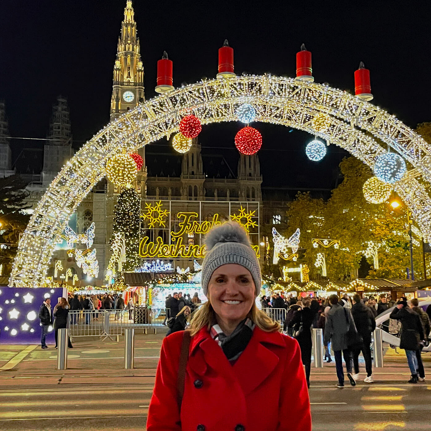Diane Frisch smiles under a lit up arch at a winter festival in Vienna