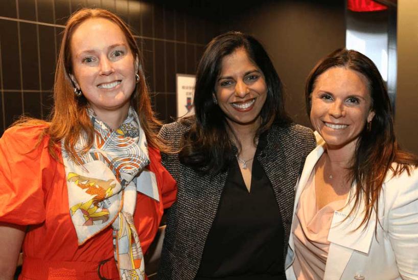Three women smiling together, posed for a group photo