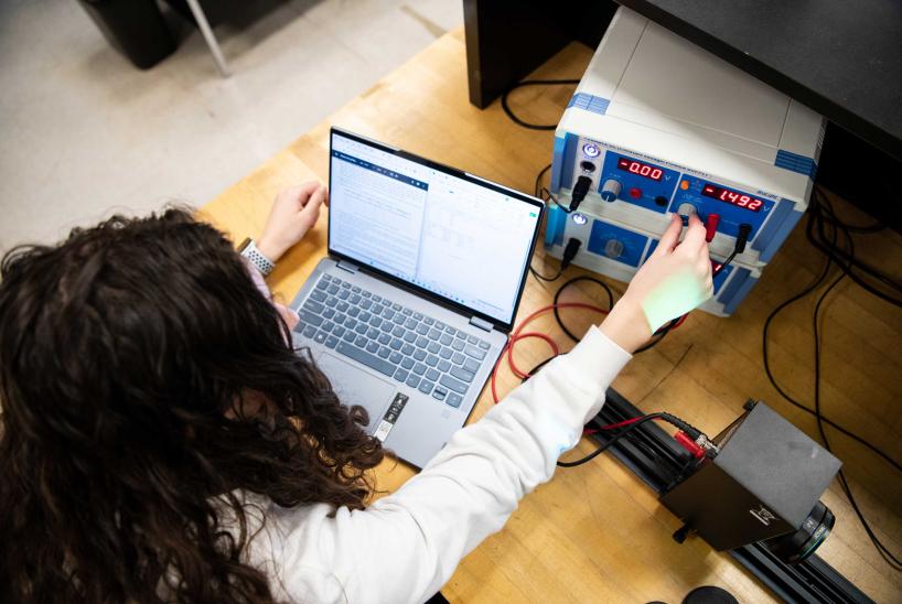 A student adjusts settings on an electronic box.