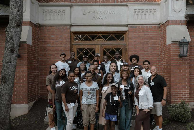 A group of Lehigh alumni and friends pose for a group photo in front of Lehigh University's Lamberton Hall.