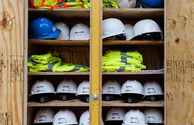A collection of stacked hard hats and safety vests