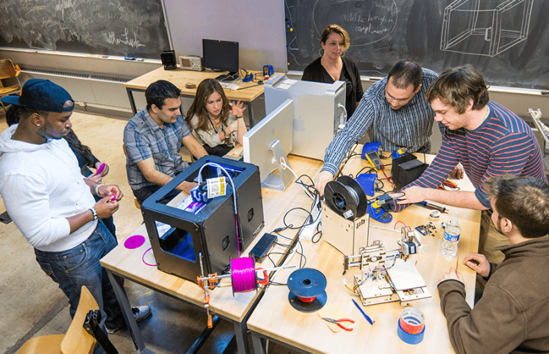 A group of Lehigh University students gather around a 3D printing project.