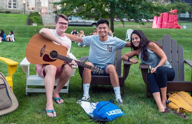 Three Lehigh University students sitting in Adirondacks chairs on the Clayton University Center lawn.