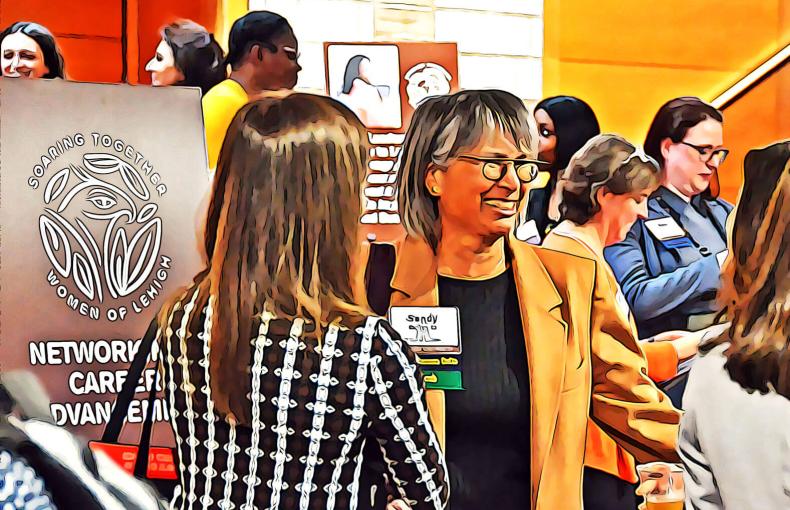 Two women standing in a crowd, mingling and smiling