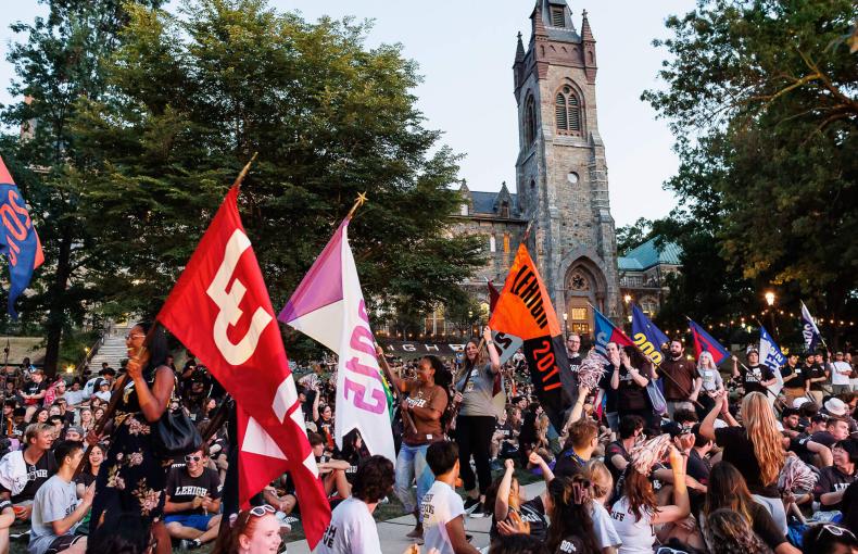 Alumni and students walk the flags through a crowd of freshmen at the rally.