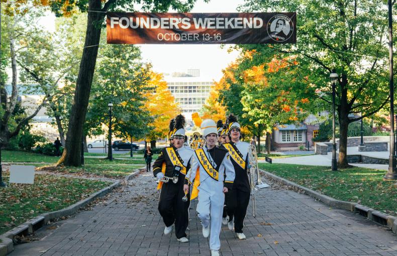 Marching 97 walking under a Founders Weekend banner