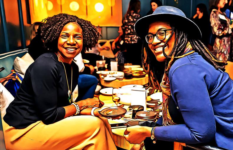 Two African American ladies sitting together and smiling