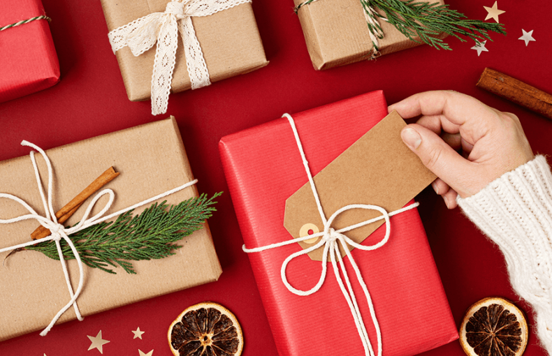 Presents of varying sizes wrapped with string and decorated with cinnamon sticks, dried oranges, pine branches, and gold stars
