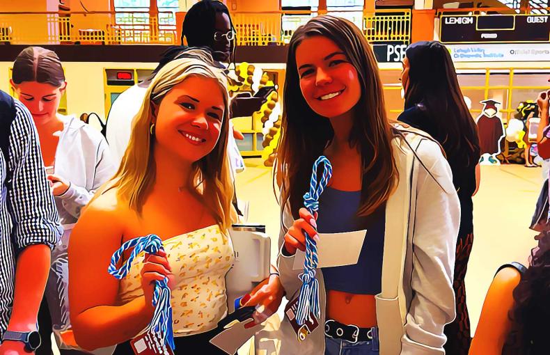 Two students smile while proudly holding their Lehigh Promise cords