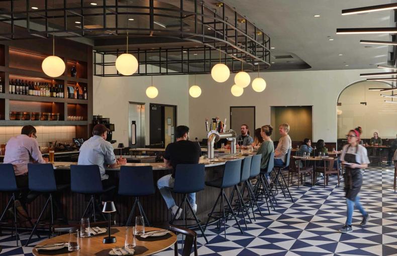 People sit at the bar and at tables for lunch.