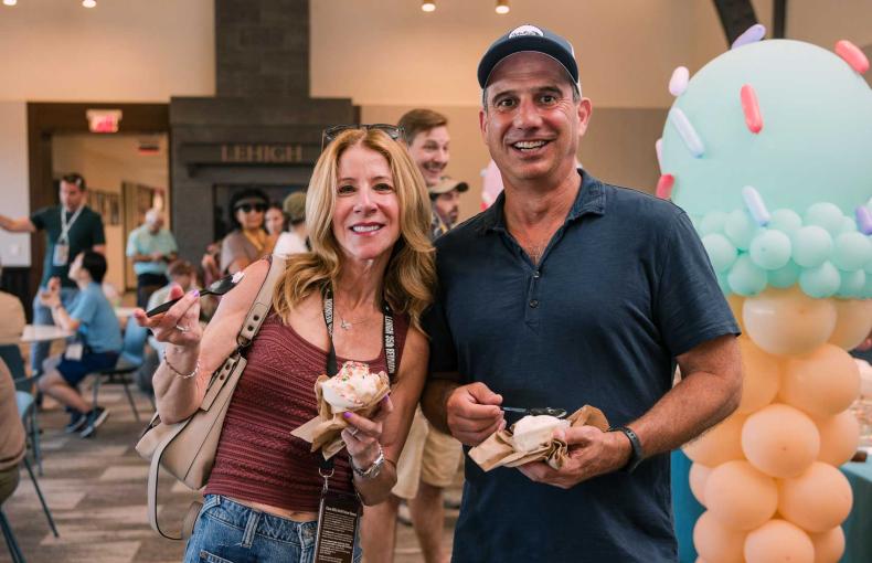 A couple stands smiling at the camera, holding their ice cream.